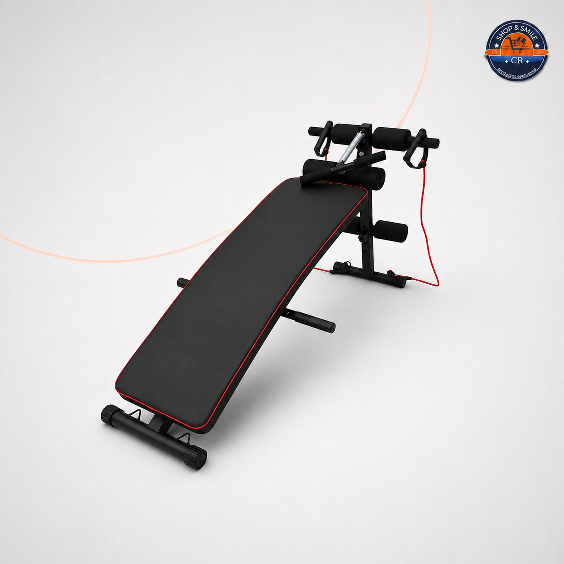Banco multifuncional inclinado para abdominales, con superficie negra acolchada y borde rojo, estructura metálica negra, rodillos de espuma para apoyo y bandas elásticas con agarraderas. La imagen muestra el banco sobre un fondo blanco junto con información promocional de sus usos y beneficios.