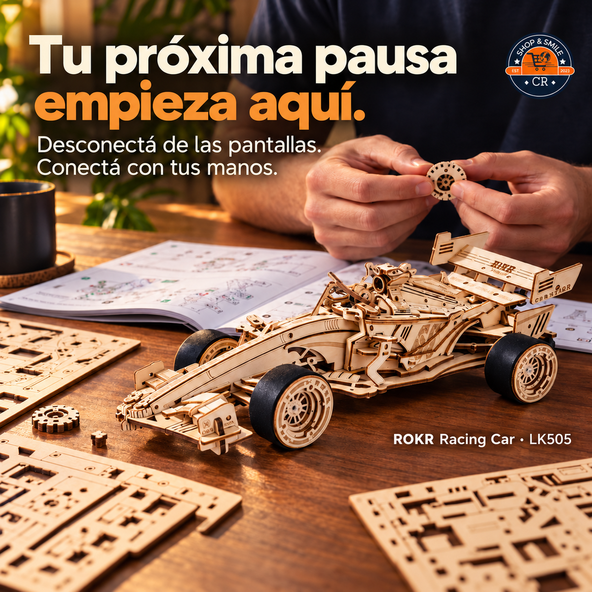 Manos de un adulto ensamblando una pieza del ROKR LK505, junto al auto, las láminas de madera y el manual.
